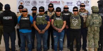 Personal de seguridad asegurando armas y drogas decomisadas