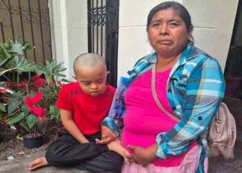 Madre con hijo en hospital infantil esperando apoyo para transporte