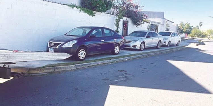 Vehículos estacionados sobre banquetas en ciudad